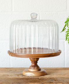 a cake on a wooden stand with a glass cover