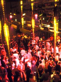 a large group of people standing around in a room with lights on the walls and floor