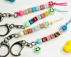 three personalized key chains with embellishments and smiley face charms on them