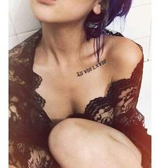 a woman with tattoos on her chest sitting in a bath room next to a tiled wall