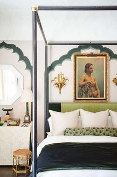 a bedroom with a four poster bed and paintings on the wall above it's headboard