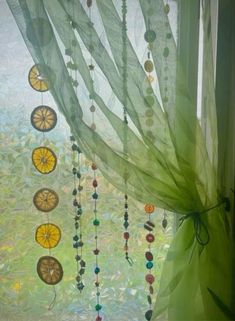 a window with beads hanging from it's side and green curtains in the background