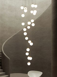 an artistic light fixture hanging from the side of a spiral staircase in a modern building