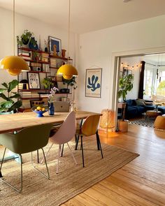 a dining room table and chairs with plants on the shelves above it, in front of a doorway