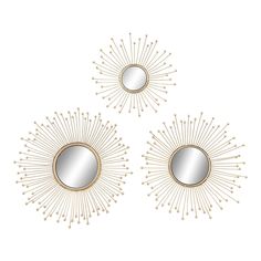 three mirrors on the wall with sunbursts around them and one is gold