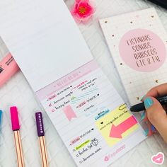 a person writing on a piece of paper next to some pens and notebooks with stickers