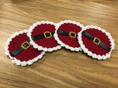 three crocheted santa claus hats sitting on top of a wooden table