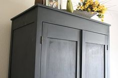 a gray cabinet with flowers and pictures on top