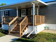 a mobile home with stairs leading up to the front door and steps down to the porch