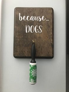 a sign that says because dogs hangs on the wall next to a toothbrush holder