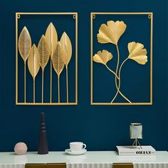 two gold metal wall art pieces on a blue wall