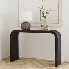 a black console table with a vase on top and a white lamp next to it