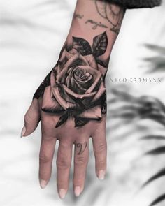 a woman's hand with a rose tattooed on the left wrist and black ink