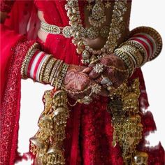 a woman in red and gold outfit with jewelry on her arm, holding hands together