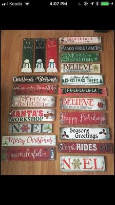 christmas signs are arranged on the floor for sale in front of a wooden table top