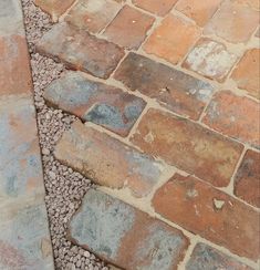 an old brick walkway with gravel on the ground