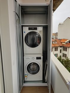 a washer and dryer are in an open cabinet on the outside of a balcony