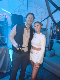 a man and woman standing next to each other in front of a blue wall with lights