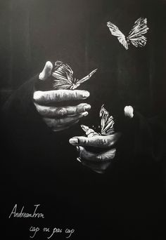 a black and white photo of two hands holding butterflies