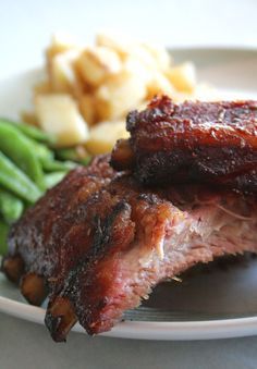 two pieces of meat on a plate with green beans and potatoes