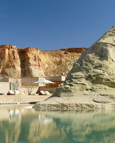 two lounge chairs sitting on the edge of a pool in front of a mountain range