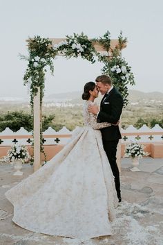 a bride and groom kissing under an arch decorated with flowers