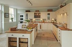 a large kitchen with lots of counter space and white cupboards, along with an island in the middle