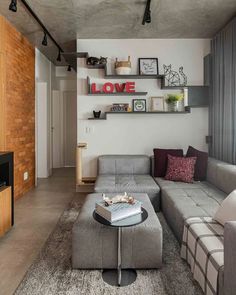 a living room with grey couches and wooden shelves on the wall above it is a coffee table