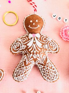 a gingerbread man ornament surrounded by other decorations and flowers on a pink surface