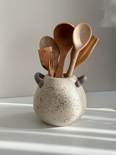 spoons, spatulas and wooden utensils in a white ceramic container