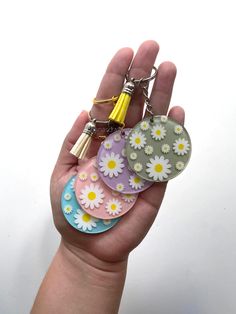 a hand holding four flower shaped key chains