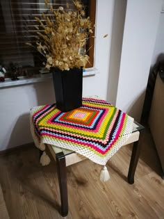 a crocheted tablecloth sits on a stool next to a potted plant