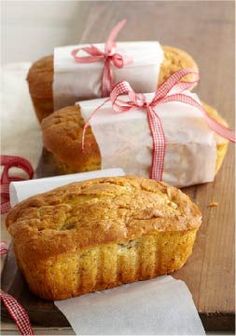 a loaf of bread sitting on top of a wooden table next to two wrapped presents