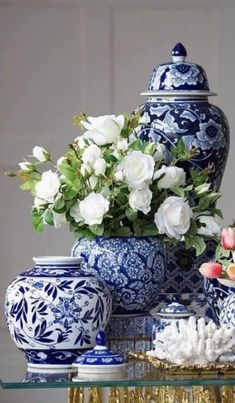 blue and white vases with flowers in them sitting on a glass top table next to other decorative objects