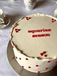 a cake with the words aquarius season written on it, surrounded by tea cups and saucers