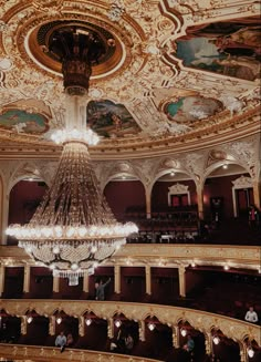 an ornate chandelier hangs from the ceiling in a large room filled with people