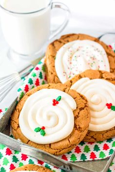 cookies with white frosting and sprinkles are on a plate next to a glass of milk