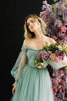 a woman in a green dress holding flowers