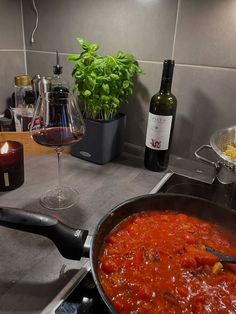 a pan filled with food sitting on top of a stove next to a bottle of wine