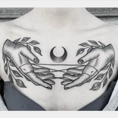 a woman's chest with two hands holding a crescent and leaves on the other side