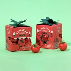 two boxes of tomato shaped snacks sitting next to each other on a green surface with tomatoes in the background