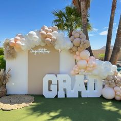 an entrance decorated with balloons and the word grad surrounded by palm trees in front of a swimming pool