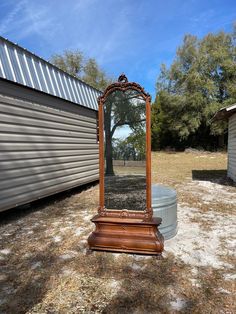 a mirror sitting on top of a wooden stand in the middle of a grass field