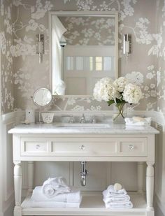 a white sink sitting under a mirror next to a wall mounted faucet with flowers on it