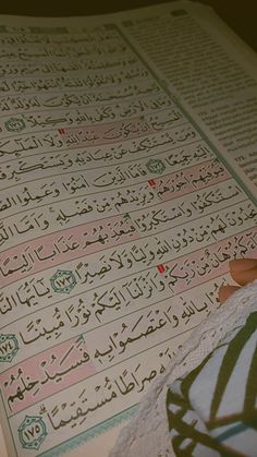 an open book with arabic writing on it and a person's hand resting on the page