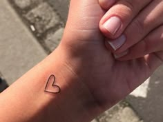 a woman's arm with a small heart tattoo on her left wrist and the word love written in it