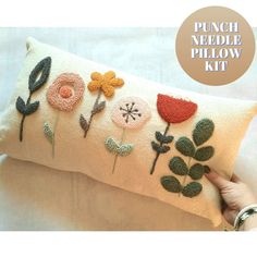 a hand holding a pillow with flowers on it