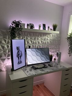 a desk with two computer monitors on top of it next to a potted plant