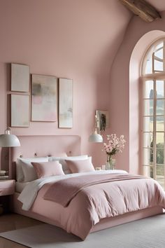 a bedroom with pink walls and white bedding, an arched window, and artwork on the wall