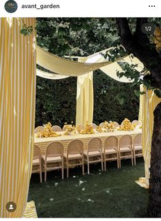 the table is set up with yellow and white striped drapes over it for an outdoor event